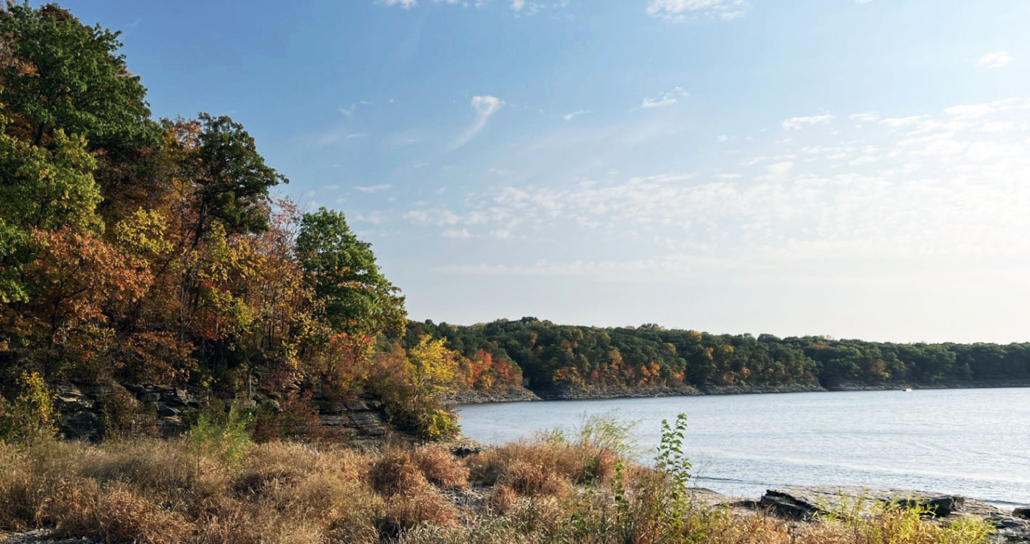 A beautiful lakeshore in autumn surrounded by trees with fall color.